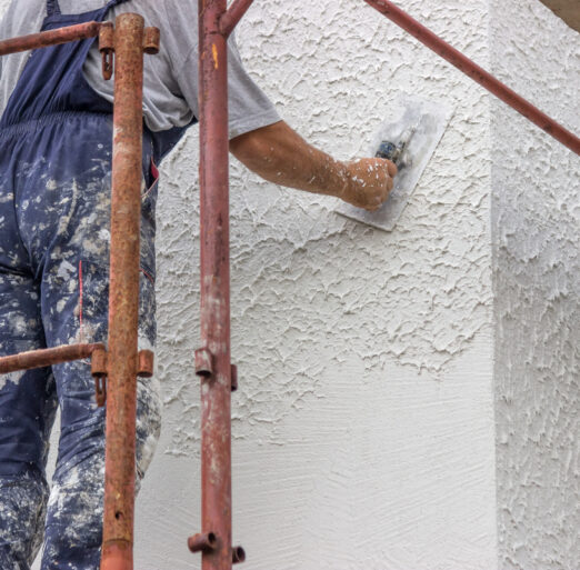 Decorative plaster, white cement based decorative top coat plaster resistant on outside whether conditions. Applied on the surface by a steel trowel. Selective focus.